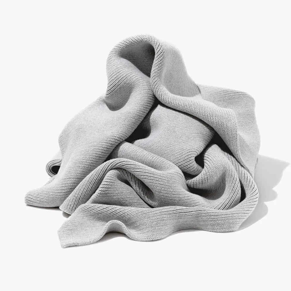 A soft light gray ribbed scarf paired with a ribbed gray organic cotton weighted blanket for bedroom use