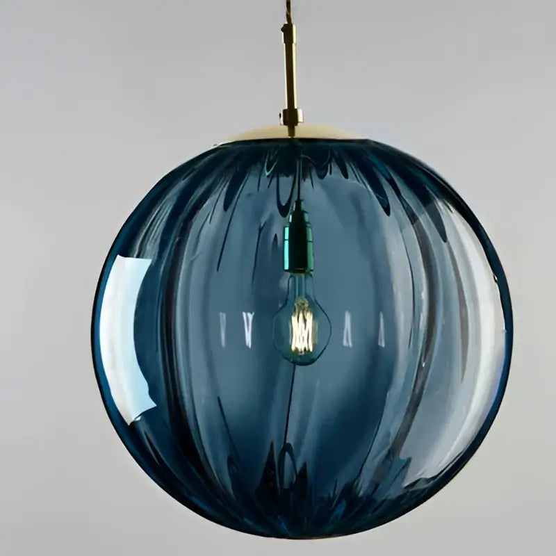Deep blue ribbed glass globe pendant light with brass fixture and exposed filament bulb in iron finish for dining room