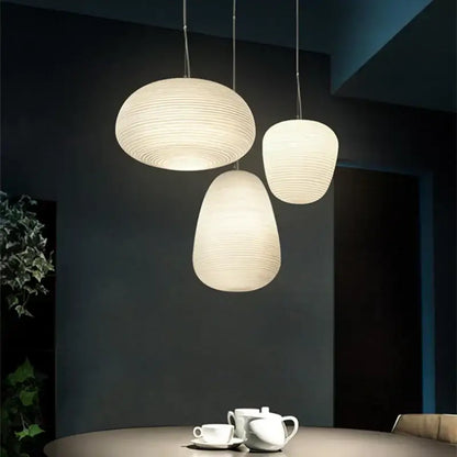 Three ribbed off-white paper glass cocoon pendant lights hang from cords as kitchen decorbites glass cocoon lamps