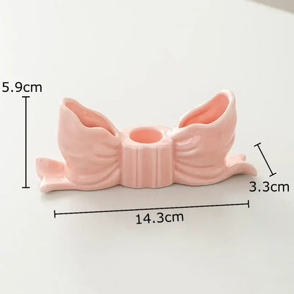 A delicate ribbed pink ceramic bowknot candle holder with two flared openings and central hole for decorbites decorbites bowknot candle