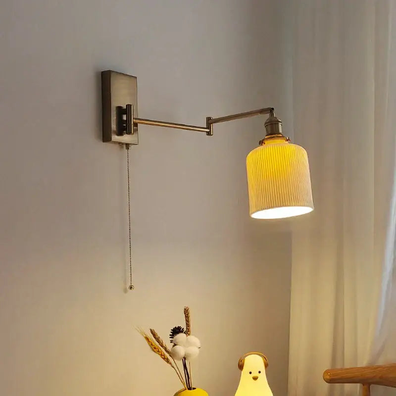 A warm yellow ribbed glass wall sconce with brass swing arm and decorbites brass swing bedroom light fixture
