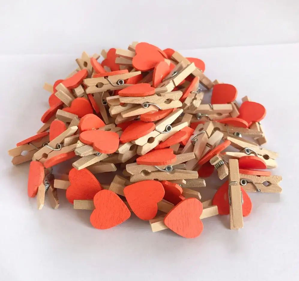 A pile of romantic heart shape wood clips with bright orange hearts and natural wood bodies for bedroom decor