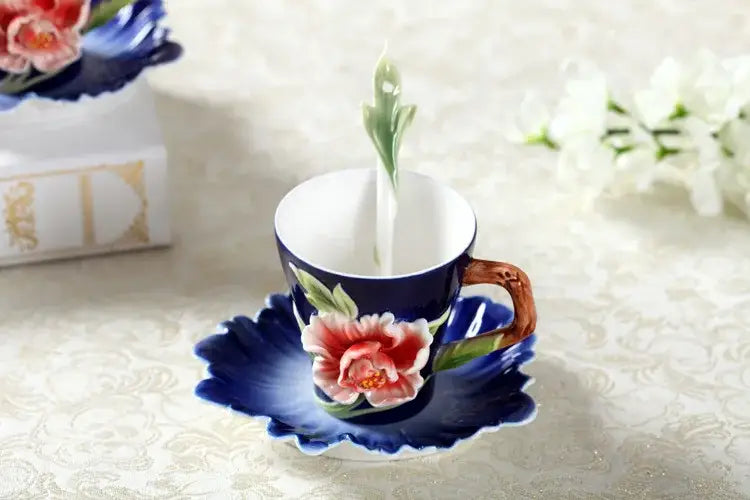 A delicate navy blue porcelain rose peony floral teacup with hand-painted pink peony on a leaf-shaped saucer