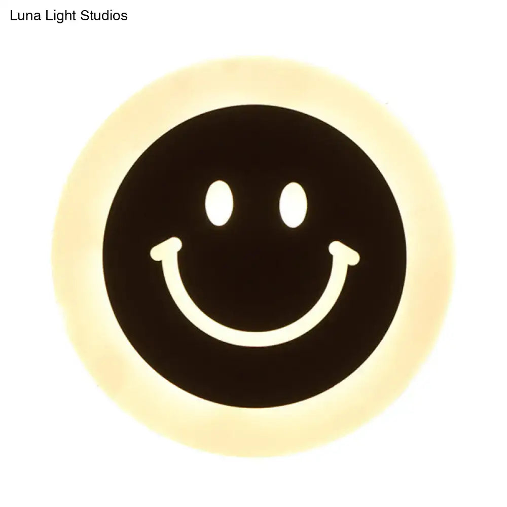 Round led smiley wall sconce with warm white light featuring a black center and white facial features on cream ring