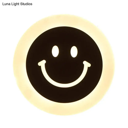 Round led smiley wall sconce with warm white light featuring a black center and white facial features on cream ring