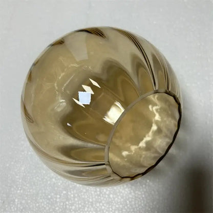 A translucent amber decorbites glass ball pendant lamp with smooth rounded shape and vertical ridges for living room decor