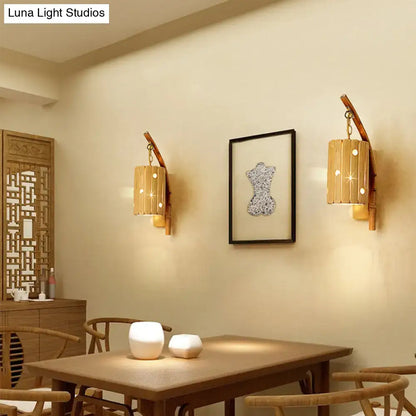Pair of rustic bamboo cylinder house sconce light fixtures with warm glowing light and decorative cutouts for bedroom walls