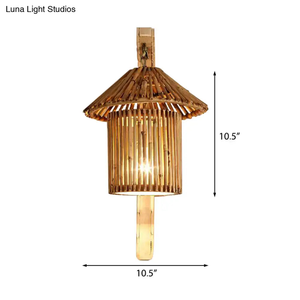 A warm-toned rustic bamboo cylinder house sconce light fixture with tiered pagoda roof and vertical slats for bedroom use