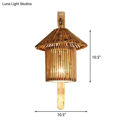 A warm-toned rustic bamboo cylinder house sconce light fixture with tiered pagoda roof and vertical slats for bedroom use