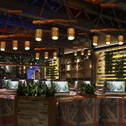 Rustic wooden beam pendant lamp with adjustable cylindrical bamboo shades hanging from chains in bamboo island lighting fixture