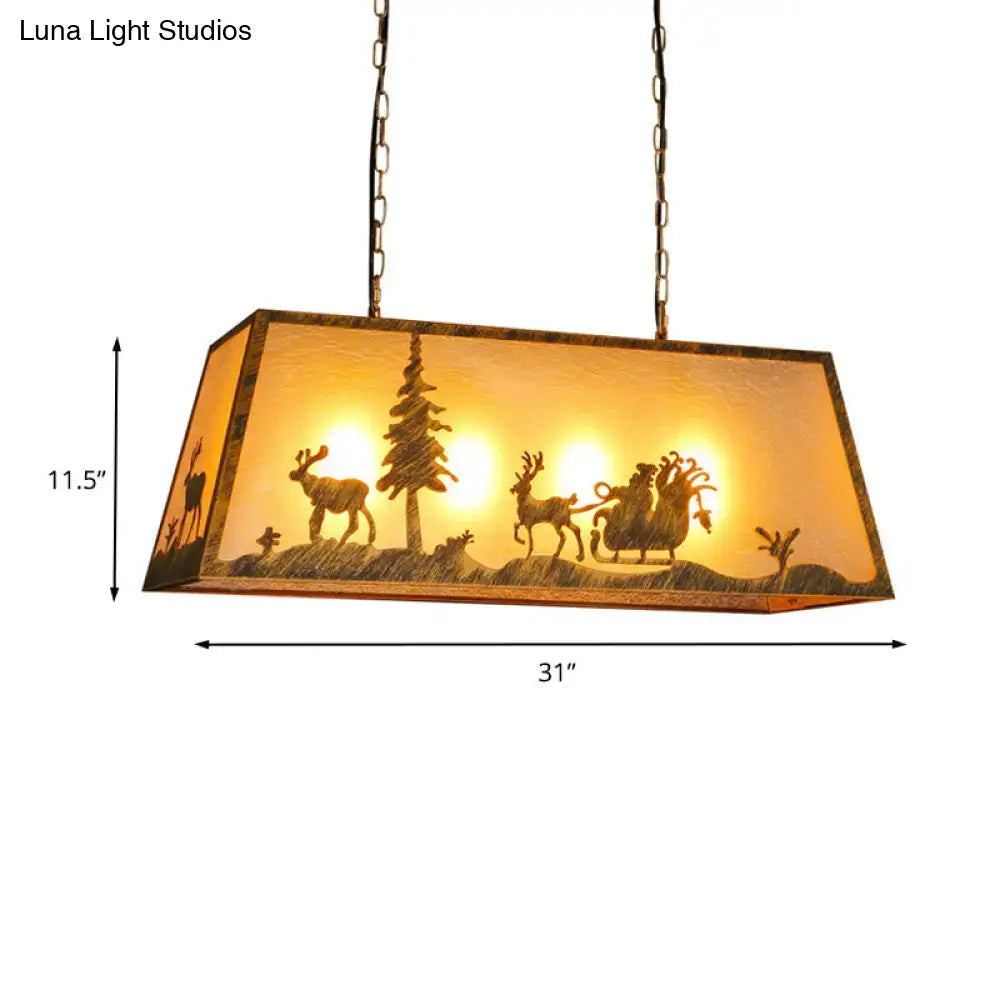 Rectangular etched linear island lamp with warm amber glass shade featuring carved reindeer santa and pine trees in beige plastic and metal