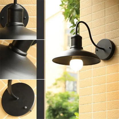 Black rustic gooseneck light fixture featuring a wrought iron curved arm and dome-shaped shade for outdoor use