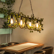 Decorbites black metal linear island lamp with five edison bulbs wrapped in rope and adorned with artificial ivy vines