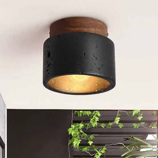 Rustic black travertine ceiling light with concrete texture and wooden top featuring warm gold interior for entrance hallway decor