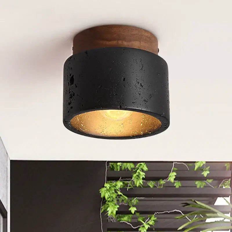 Rustic black travertine ceiling light with concrete texture and wooden top featuring warm gold interior for entrance hallway decor