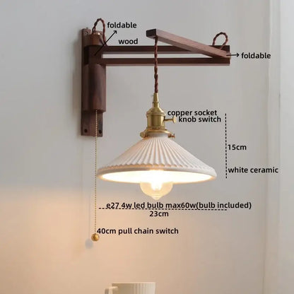 A white ceramic wall sconce with a fluted shade hangs from a foldable wooden arm with brass hardware decorbites clear glass