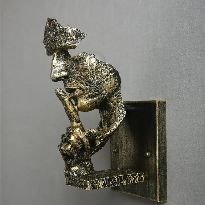 Antique bronze sculptural wall lamp featuring a textured loft face wall figure in a shh gesture for decorbites loft face decor
