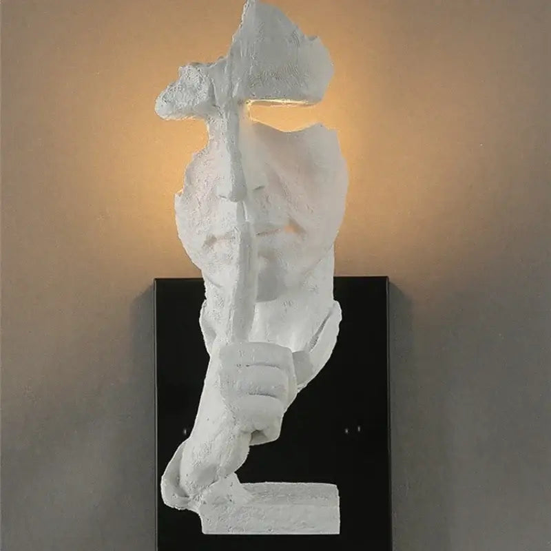 White sculptural wall lamp with textured abstract human face and warm lit eye for decorbites loft face wall decor