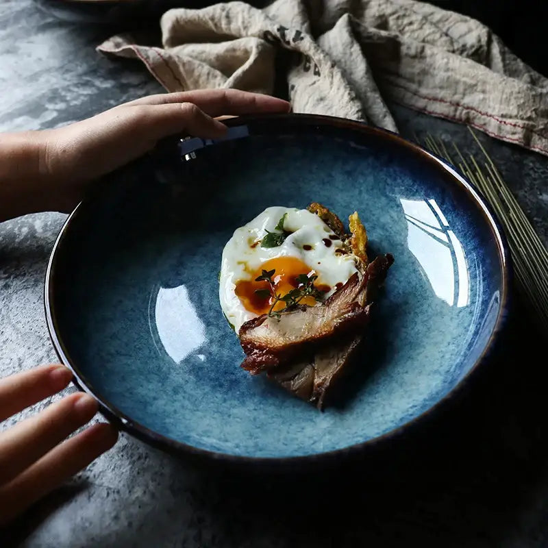 Rustic deep blue speckled decorbites ceramic salad bowl with dark rim holding plated egg and meat dish