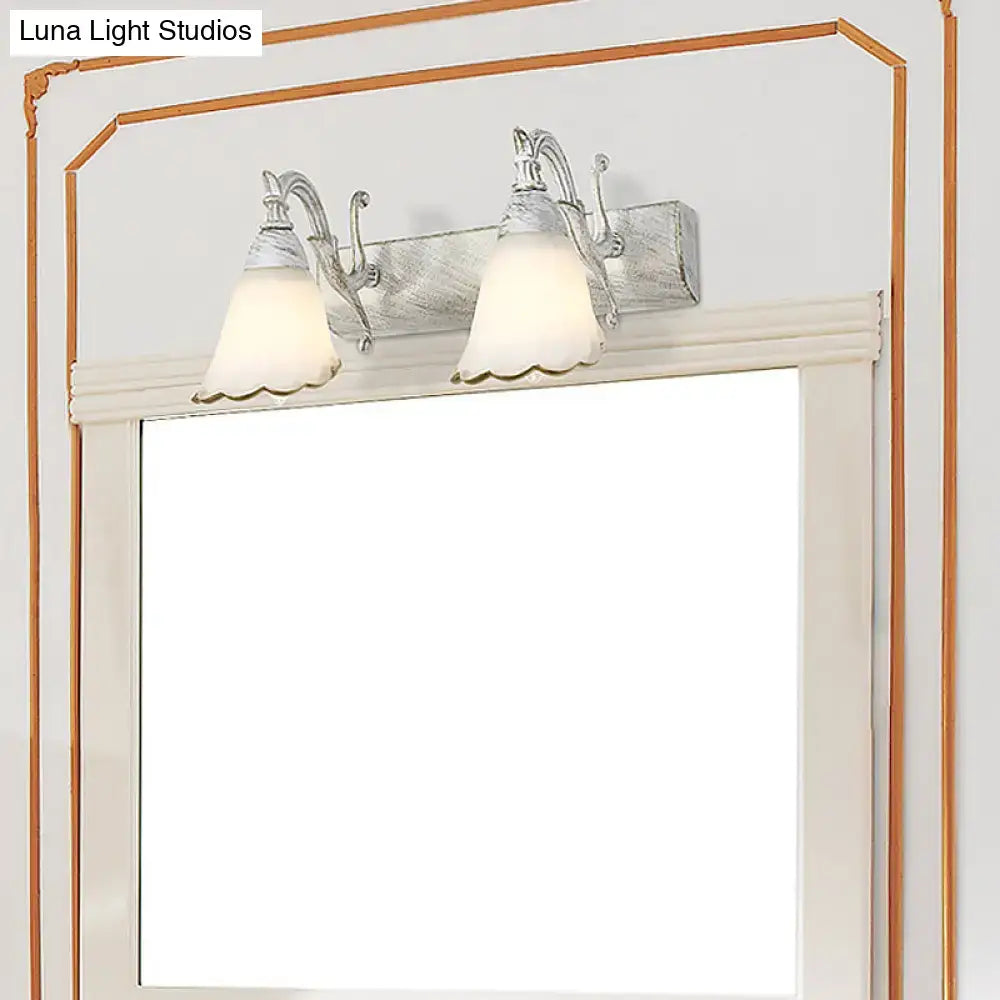 Silver-finished double-light wall light with frosted glass shades and ornate metal arms in rustic distressed white 110v-120v