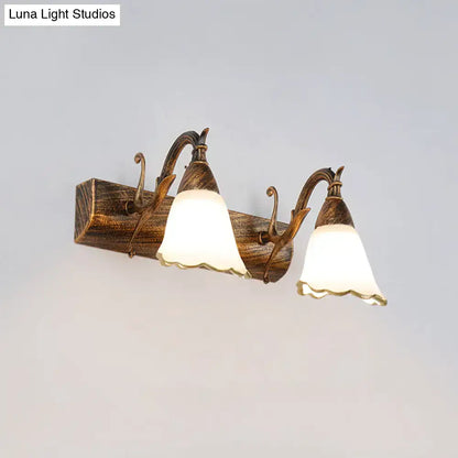 Antique bronze-finished wall light with two frosted bell-shaped shades on rustic distressed white wood 110v-120v