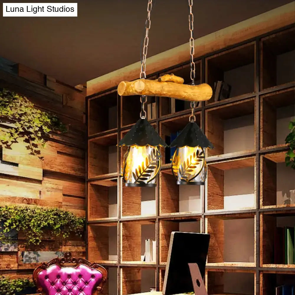 Rustic wooden branch pendant light with two black metal leaf cutout lanterns and warm glow clear glass shade