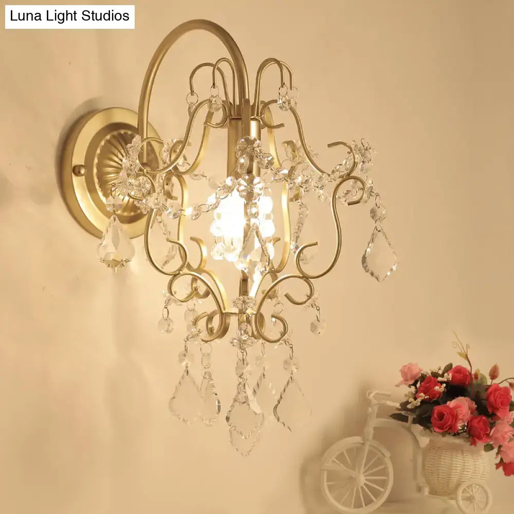 Rustic gold crystal wall mount lamp with ornate gold-toned wrought iron and dangling crystal droplets as wall mount lamp