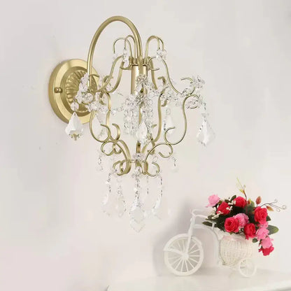 Rustic gold crystal wall mount lamp with gold-toned ornate design and dangling clear crystal droplets for bedroom use