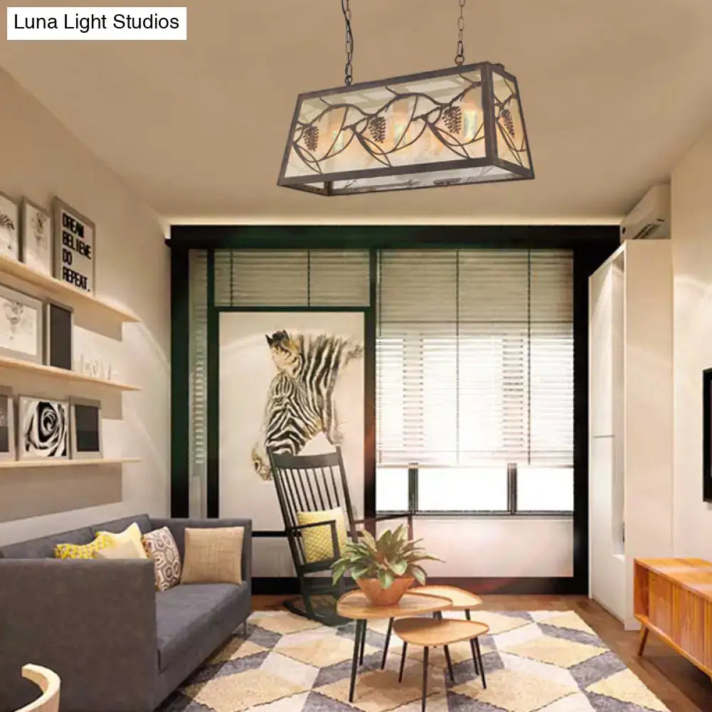 Rectangular dark metal frame island light fixture with stained glass panels featuring rustic grapevine leaf patterns