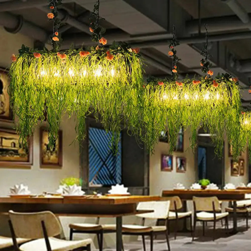 Rustic iron rose pendant light fixture with green cascading vines orange flowers and warm glowing bulbs with chain cord length