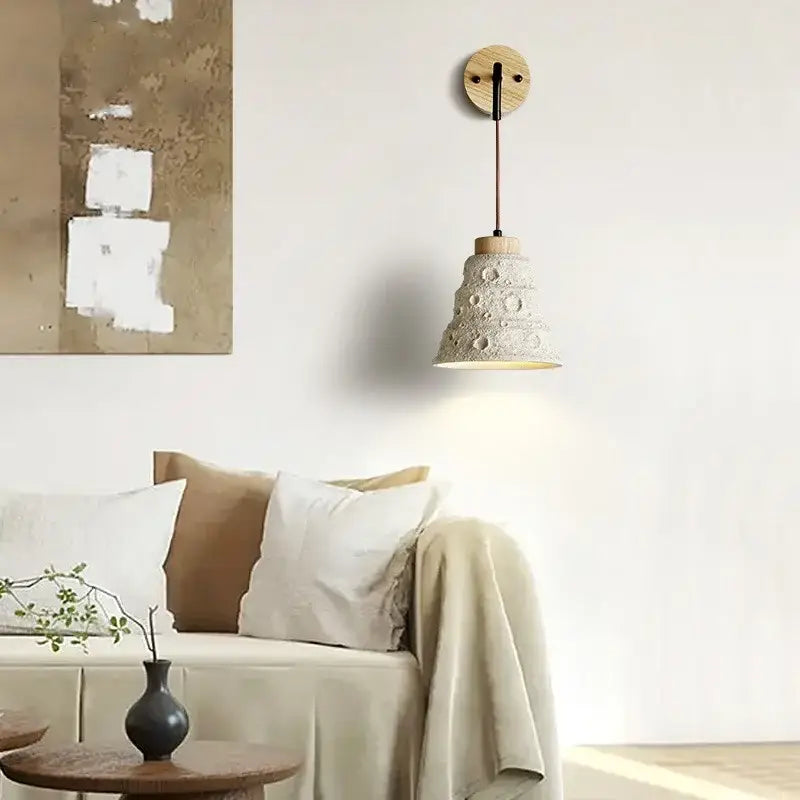 Rustic moon cement led wall lamp featuring an off-white textured ceramic pendant with wooden base and black cord decorbites cement led