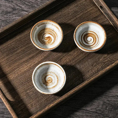 Three rustic white speckled ceramic seasoning sauce dishes with brown spiral patterns on a dark wooden tray decorbites ceramic seasoning
