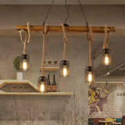 Rustic wooden beam chandelier with thick natural rope suspending five black metal mesh pendant light cages