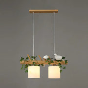Decorbites modern wood linear island lighting with warm cylindrical shades and maple leaf plant accents on natural wood branch