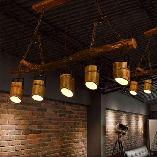 Rustic wood linear island pendant light featuring five brass-colored cylindrical lights hanging from a wooden beam