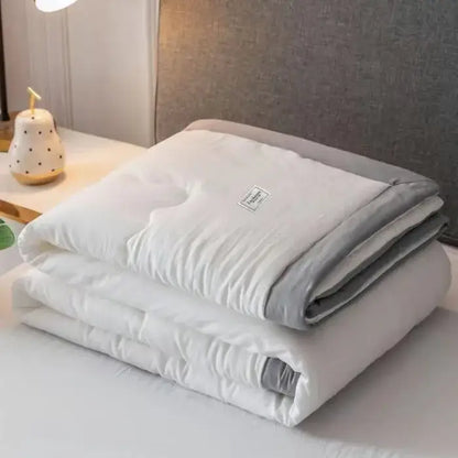 A soft white and gray decorbites cooling cotton quilt with subtle texture and label, ideal as a bedroom blanket