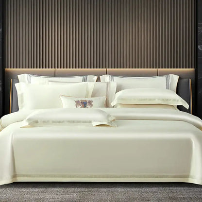 Cream-colored satin egyptian cotton duvet cover set with gold trim and embroidered crest on central pillow