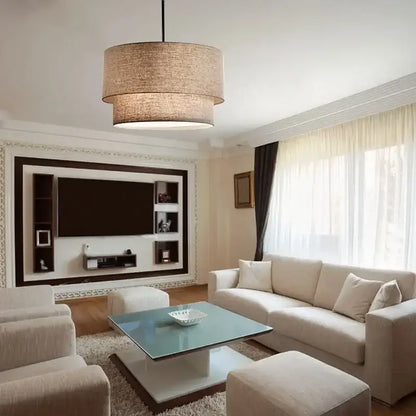 Beige cylindrical Scandinavian pendant light with double linen fabric shade hanging in dining room ceiling