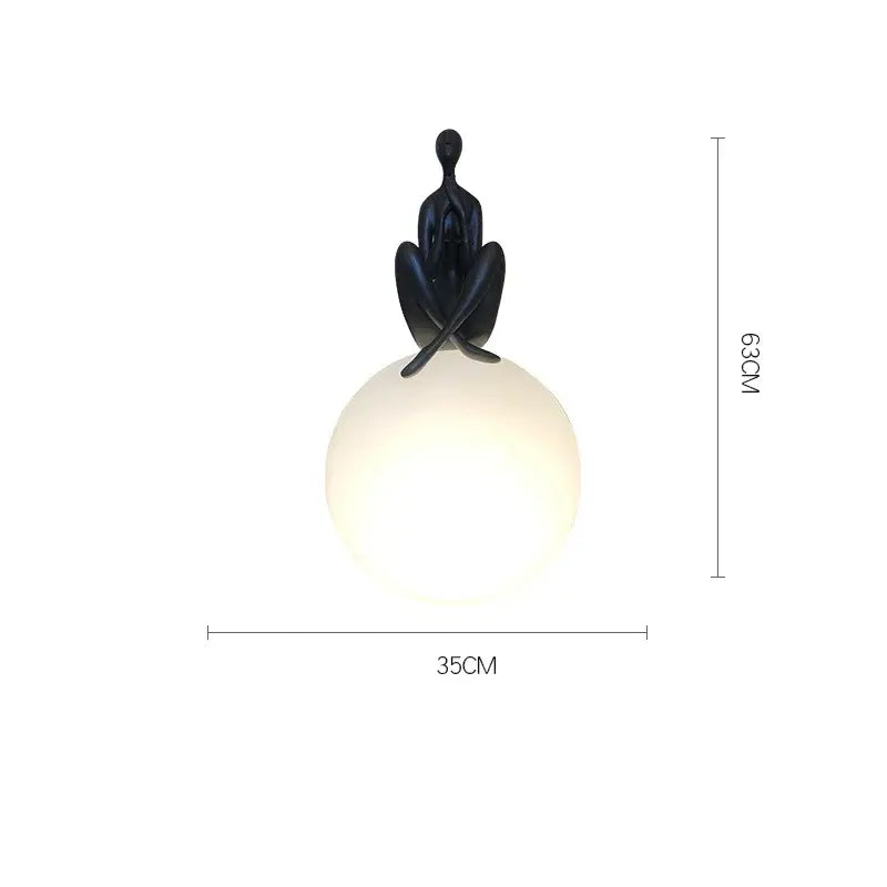 Black sculpted figure perched atop a glowing red and black glass ball table lamp for decorbites glass ball decor