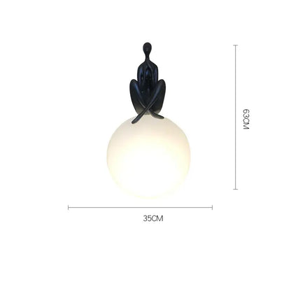 Black sculpted figure perched atop a glowing red and black glass ball table lamp for decorbites glass ball decor