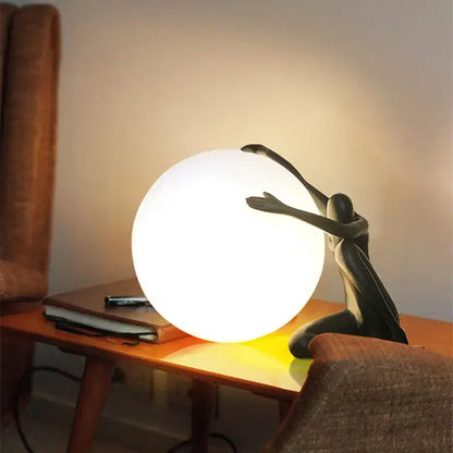 A sleek matte black figurine table lamp with a glowing white glass ball decorbites glass ball for bedroom decor