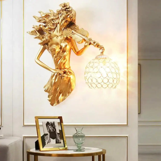 Sculptural gold wall lamp featuring a violin-playing female figure with an ornate crystal wall lamp globe shade