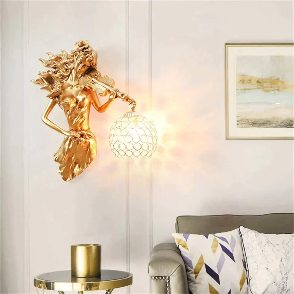 Sculptural gold wall lamp featuring a violinist figure with flowing hair and an ornate crystal wall globe shade
