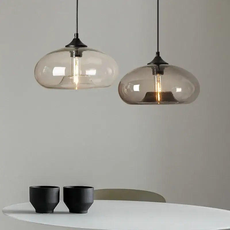 Two modern pendant lights with frosted glass shades and exposed filament bulbs complement decorbites colorful glass pendant set