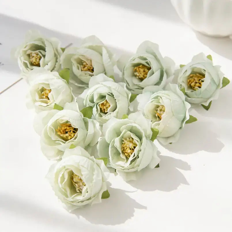 A cluster of delicate pale green silk peony flowers with soft layered petals and golden yellow centers for decor