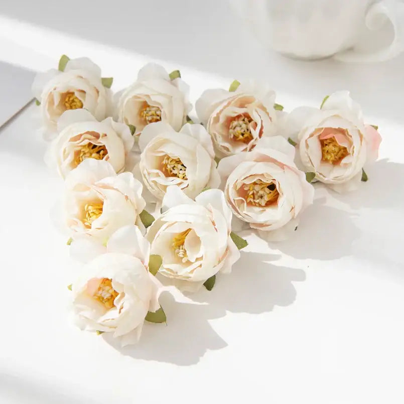 A cluster of cream-colored silk peony flowers with pink blush accents and golden-yellow centers for wedding decor