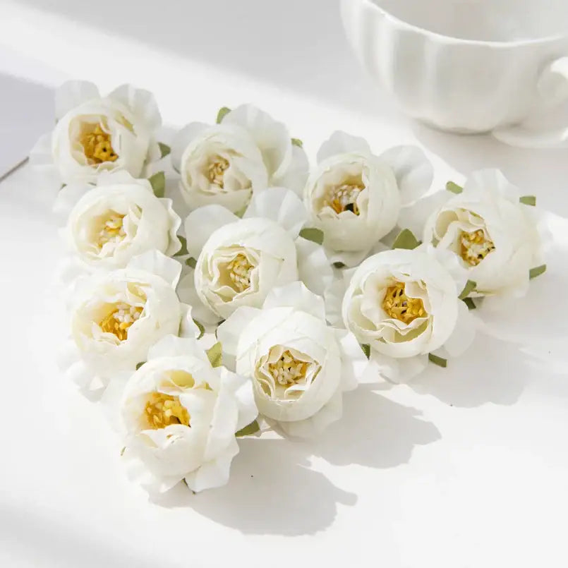 A cluster of delicate white silk peony flowers with soft layered petals and golden centers for wedding decor