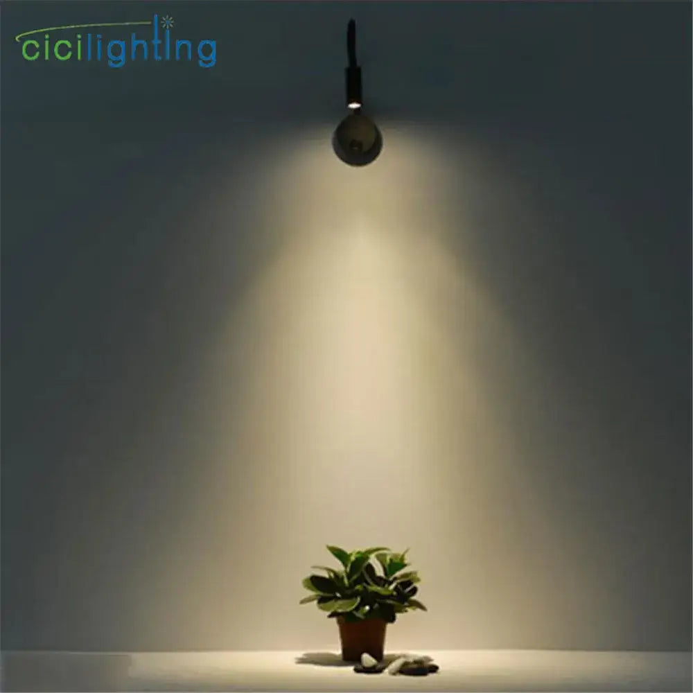 A sleek black flexible gooseneck led wall sconce from cicilighting casts warm light on a small potted plant for reading