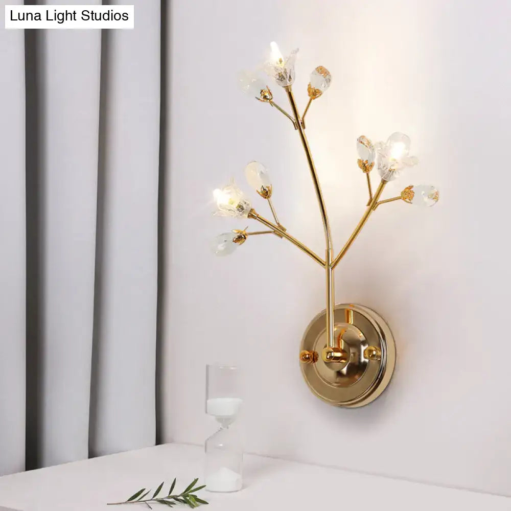 Gold-toned wall sconce with delicate branch arms and clear crystal flowers for bedroom lighting fixture