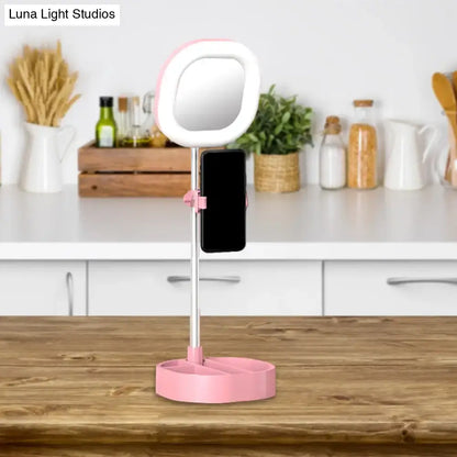 Pink circular vanity led mirror light with white led ring and phone holder on matching pink base for bedroom use